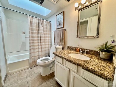 Bathroom with a skylight, toilet, vanity, shower / bath combo with shower curtain, and tile patterned flooring