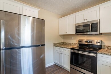 Kitchen featuring white cabinetry, appliances with stainless steel finishes, dark hardwood / wood-style flooring, and stone counters