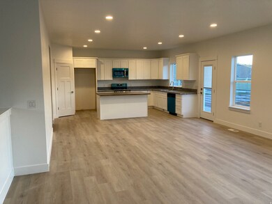 Kitchen featuring dark countertops, recessed lighting, white cabinetry, light LVP floors, and stainless steel appliances