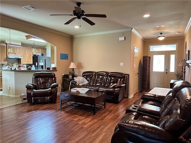 Living room featuring a ceiling fan, dark wood-sty