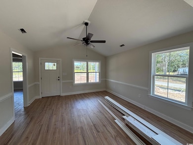 Foyer entrance with wood finished floors, vaulted ceiling, and ceiling fan