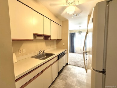 Kitchen with white appliances, light countertops, ceiling fan, decorative light fixtures, and a chandelier