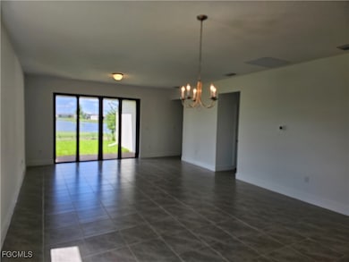 Empty room with a chandelier, dark tile patterned floors, and a water view