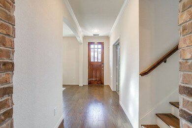 Entryway featuring stairs, ornamental molding, wood finished floors, and arched walkways