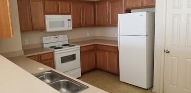 Kitchen featuring white appliances, brown cabinets, and light countertops