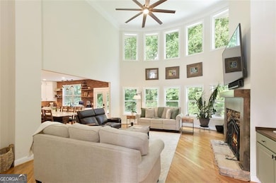 Two story living room with wall of windows for natural lighting and view to kitchen