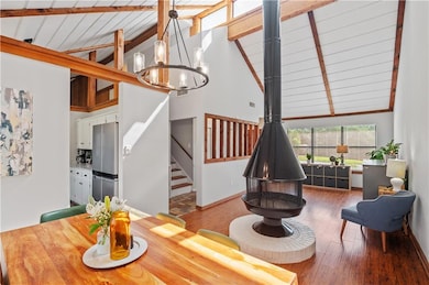 Dining area featuring a chandelier, wood finished floors, high vaulted ceiling, stairway, and baseboards