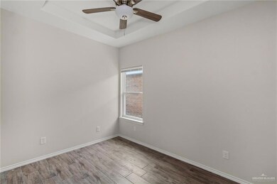 Unfurnished room featuring a tray ceiling, hardwood / wood-style floors, and ceiling fan