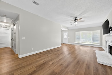 The bright and open living room seamlessly connects to the entryway and a hallway, featuring stylish wood-look flooring and a cozy fireplace.
