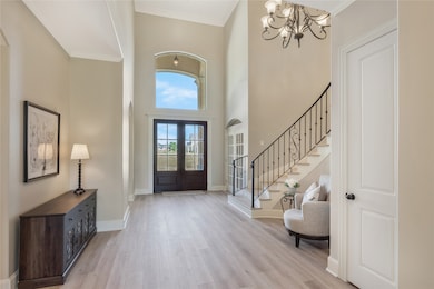 The grand foyer showcases dramatic height, a gorgeous chandelier, and abundant natural light pouring through the tall front windows. This striking entry creates a show-stopping first impression from the moment you walk in.