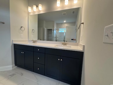 Bathroom with double vanity, a stall shower, marble look tiles, and baseboards