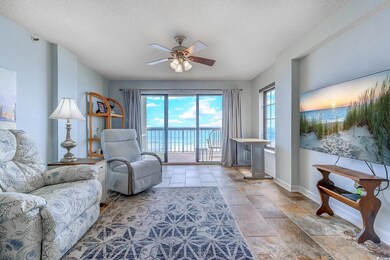 Living area featuring a ceiling fan, a textured ceiling, and light stone finish flooring