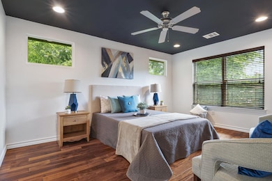 Bedroom with multiple windows, wood finished floors, baseboards, and recessed lighting