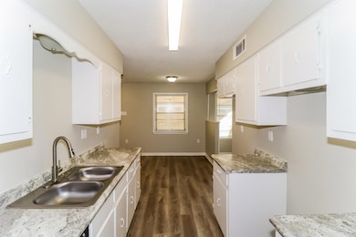 Kitchen featuring dark wood-style flooring, white cabinets, and light countertops