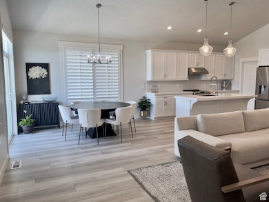 Living area featuring light wood-type flooring, a textured ceiling, recessed lighting, and a chandelier