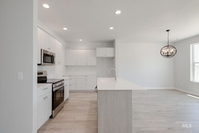 Kitchen featuring stainless steel appliances, light wood-style floors, light countertops, recessed lighting, and decorative light fixtures