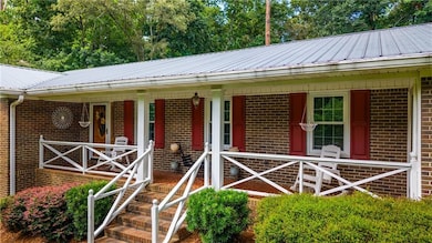 View of front of home featuring a metal roof, brick siding, and a porch