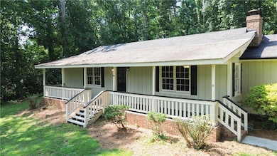 View of front of house with covered porch, a chimney, stairs, and a shingled roof