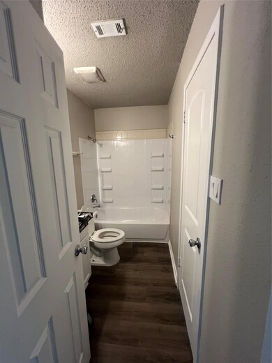 Full bath with toilet, wood finished floors, a te
