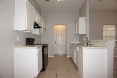 Kitchen with black range with electric stovetop, a peninsula, white cabinetry, and light tile patterned floors