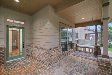 Cozy, covered front porch featuring brick flooring, a swing bench, and an elegant green front door with glass panels. The space offers a welcoming entrance to the​​‌​​​​‌​​‌‌​​​‌​​‌‌​‌‌‌​​‌‌​‌‌‌​‌​​​‌‌​ home.