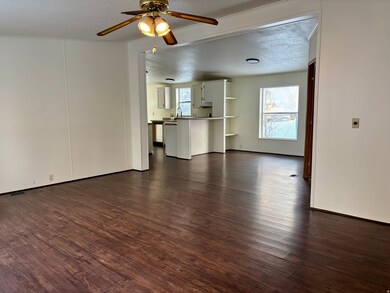 Unfurnished living room with dark wood-style floors, a textured ceiling, and ceiling fan
