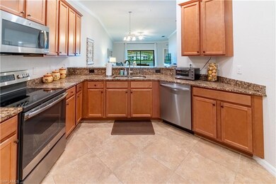 Kitchen with stainless steel appliances, sink, crown molding, vaulted ceiling, and an inviting chandelier