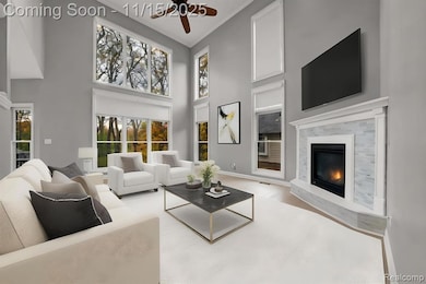 Living area featuring crown molding, wood finished floors, a fireplace, a ceiling fan, and a high ceiling