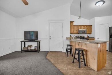 Kitchen featuring a breakfast bar, a peninsula, high vaulted ceiling, electric range, and tile patterned flooring