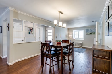 Dining space with crown molding, dark wood-type flooring, plenty of natural light, and a chandelier