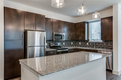 Kitchen featuring stainless steel appliances, wood-type flooring, sink, and light stone counters