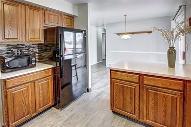 Kitchen with pendant lighting, light hardwood / wood-style flooring, black appliances, and backsplash