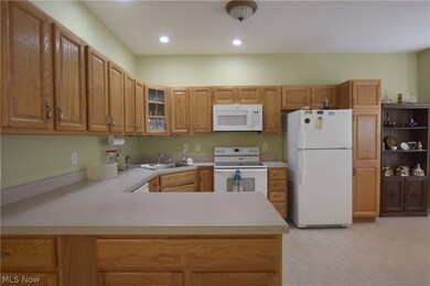 Kitchen featuring sink, white appliances, light tile floors, and kitchen peninsula