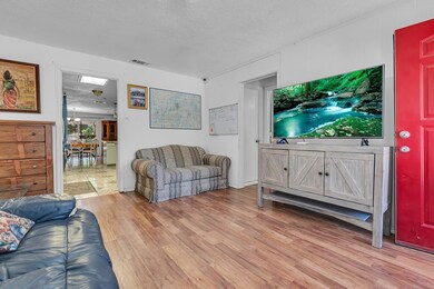 Living room featuring a skylight, a textured ceiling, light hardwood / wood-style flooring, and an inviting chandelier