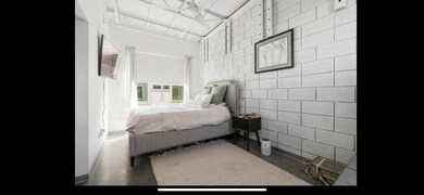 Bedroom featuring tile walls and concrete flooring