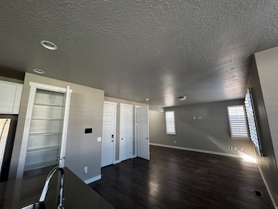 Unfurnished living room featuring dark wood-style floors and a textured ceiling