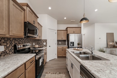 Kitchen with appliances with stainless steel finishes, hanging light fixtures, decorative backsplash, dark wood-type flooring, and recessed lighting