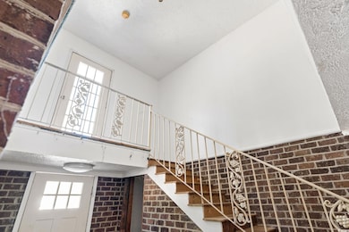 Stairs featuring brick wall, vaulted ceiling, a te