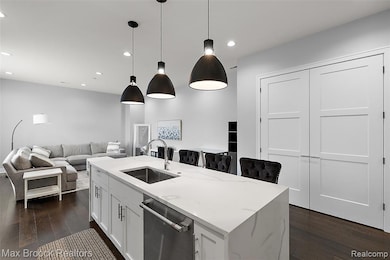 Kitchen with white cabinetry, dark wood-type flooring, dishwasher, light stone counters, and recessed lighting