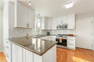 Kitchen with sink, peninsula, white cabinets, and