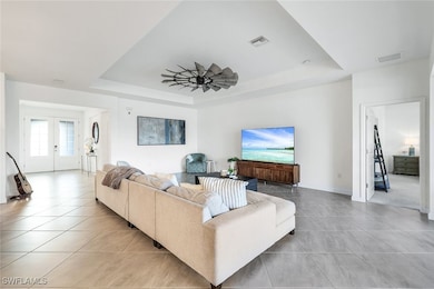 Living room with french doors, a tray ceiling, lig