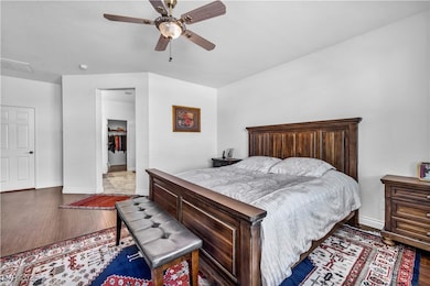 Bedroom featuring wood finished floors, a spacious closet, and ceiling fan