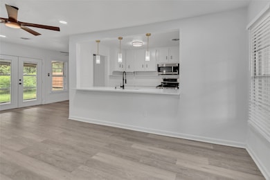 Kitchen with white cabinets, light wood-style flooring, pendant lighting, stainless steel appliances, and recessed lighting