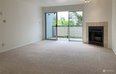 Living room with brand-new neutral-color carpet. Formica®-style counter for pass-through service from kitchen to living room. Tile-faced, wood-burning fireplace with brushed-nickel lighting above. Oversized sliding-glass door with screen door to balcony deck, and sizeable storage closet (35.5” x 49” x 93” high). Open balcony deck with exterior lighting.