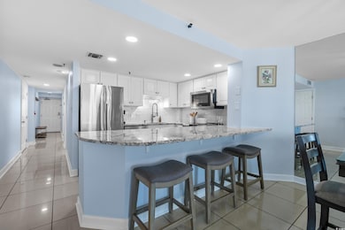 Kitchen with stainless steel appliances, light stone counters, a peninsula, light tile patterned floors, and recessed lighting