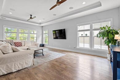 Living area with ceiling fan, a raised ceiling, hardwood / wood-style flooring, and recessed lighting
