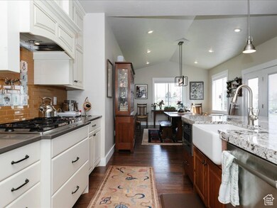 Kitchen featuring white cabinetry, tasteful backsplash, a sink, dark wood finished floors, and stainless steel appliances