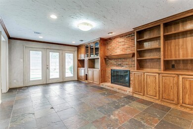 Unfurnished living room with dark tile floors, a brick fireplace, a textured ceiling, brick wall, and ornamental molding