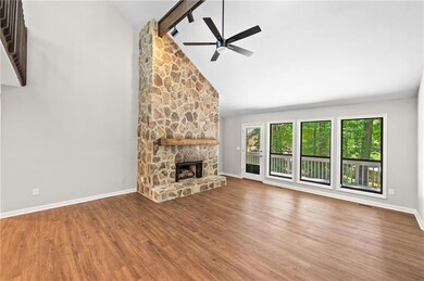 Unfurnished living room featuring wood finished floors, a ceiling fan, high vaulted ceiling, beam ceiling, and a fireplace