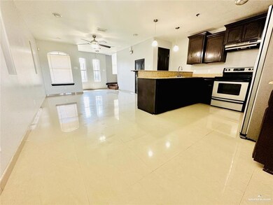Kitchen with a sink, dark brown cabinetry, open floor plan, light tile patterned floors, and electric range oven